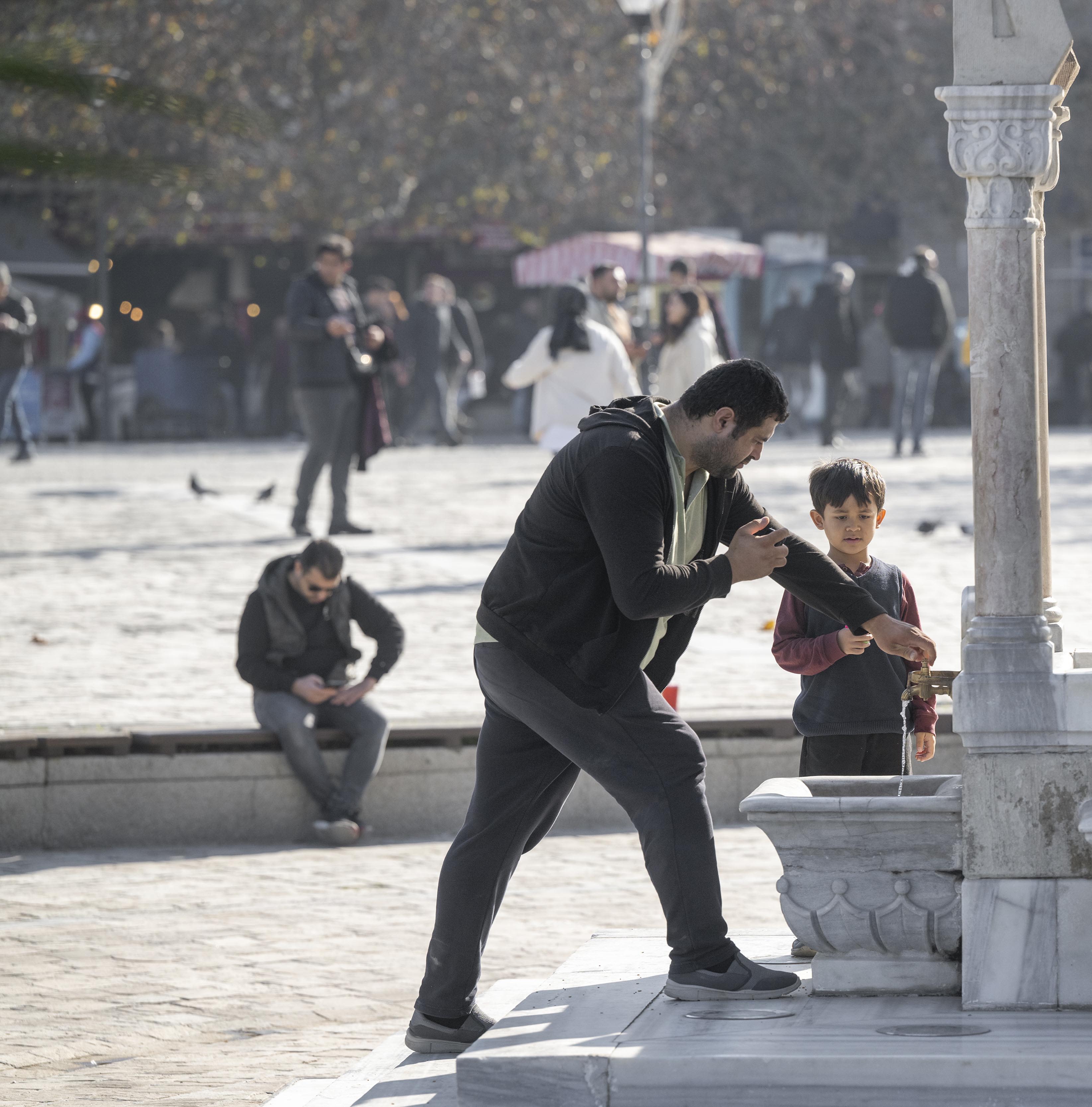 Un père et son fils se rafraichissent aux fontaines publiques de la place Konak.
