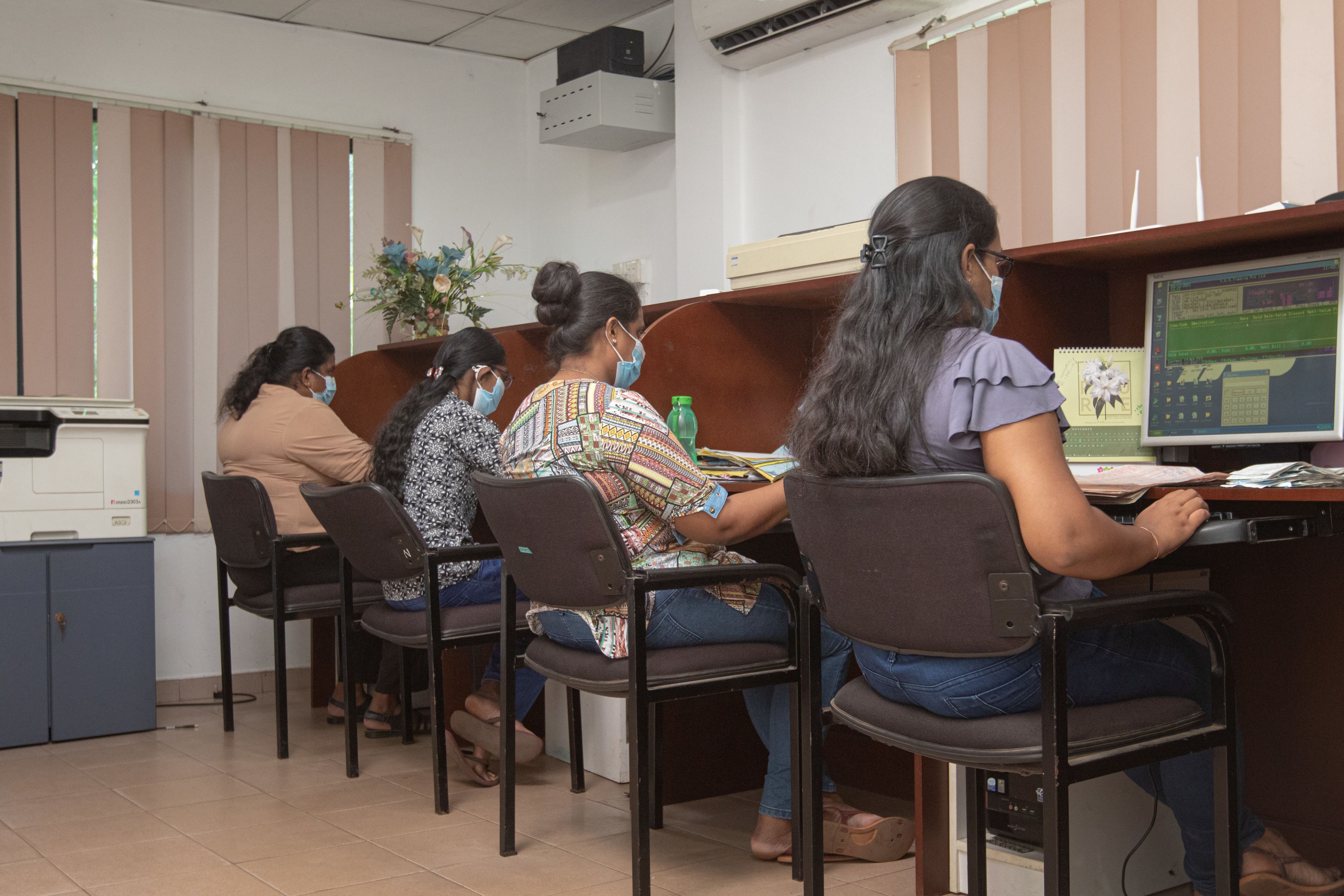 Women at a food distribution company in Sri Lanka work on company computers.