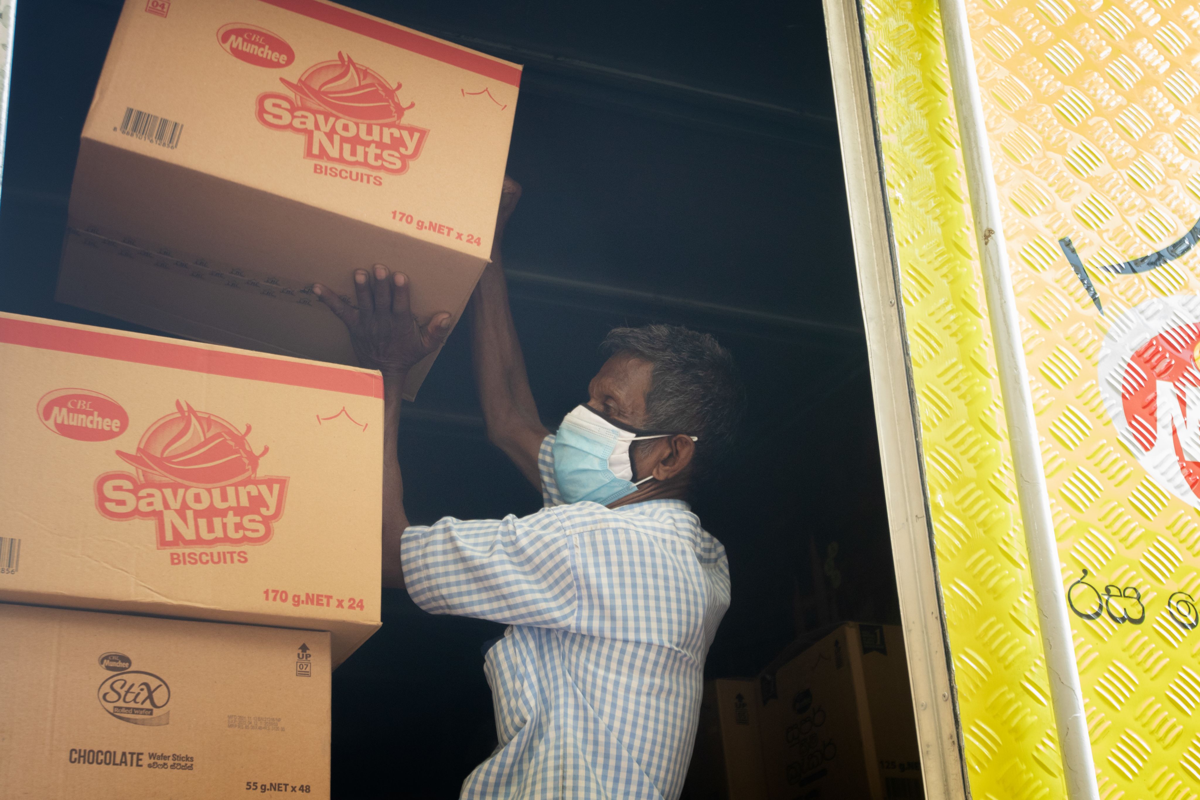 A worker in Sri Lanka loads boxes of food into a truck for distribution.