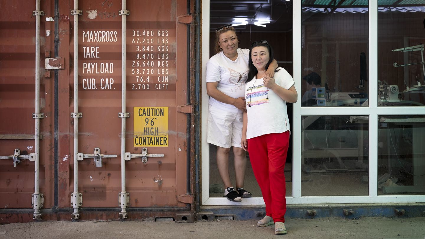 Altynai Arzymatova and her sister in front of her shipping-container converted sewing shop. 